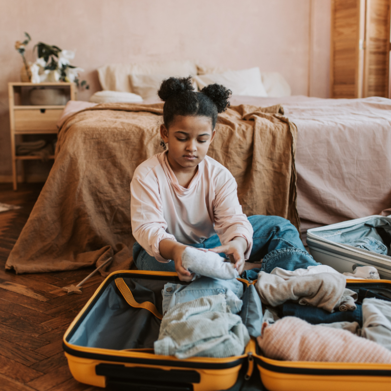 young girl packing a suit case becasue of parental relocation
